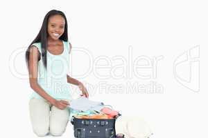 Smiling young woman packing her suitcase