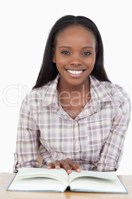 Young woman sitting behind the table reading a book