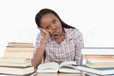 Young woman sitting on her desk with piles of books