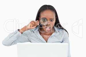 Businesswoman using a magnifying glass to look at her laptop
