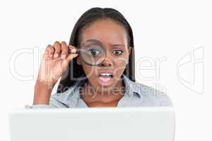 Businesswoman using a magnifying glass to look at her notebook