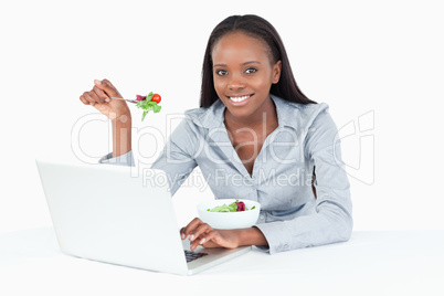 Businesswoman working with a notebook while eating a salad