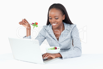 Young businesswoman working with a notebook while eating a salad