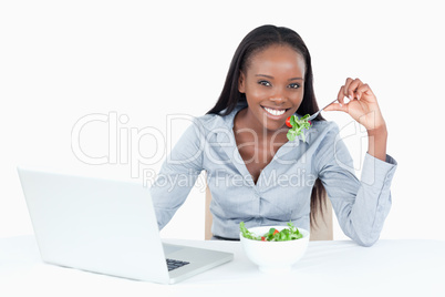 Cute businesswoman working with a notebook while eating a salad