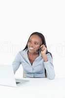 Portrait of a woman making a phone call while using a notebook