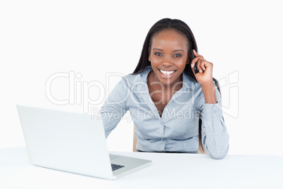 Businesswoman making a phone call while using a laptop