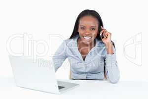 Businesswoman making a phone call while using a laptop