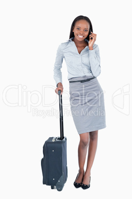 Portrait of a businesswoman with a suitcase making a phone call