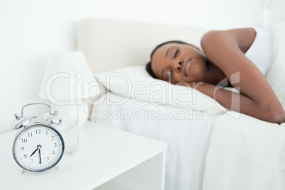 Woman sleeping while her alarm clock is ringing