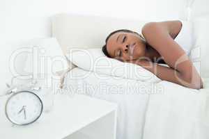 Young woman sleeping while her alarm clock is ringing