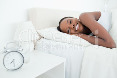 Woman waking up with her alarm clock