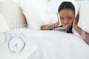 Young woman being awakened by her alarm clock