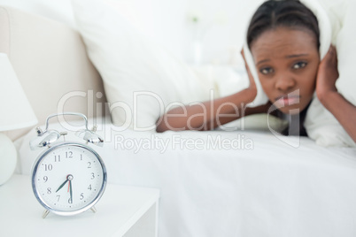 Cute woman being awakened by her alarm clock