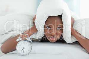 Exhausted woman covering her ears with a duvet