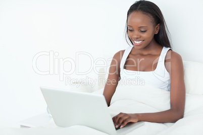 Smiling woman using a laptop before sleeping