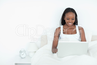 Smiling woman using a notebook before sleeping