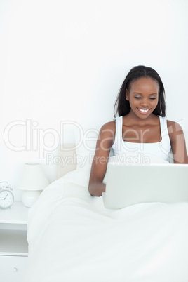 Portrait of a smiling woman using a notebook before sleeping