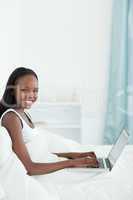 Portrait of a woman using a laptop on her bed