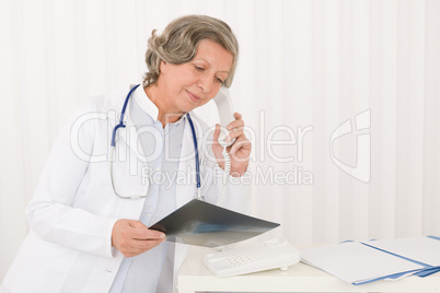 Senior doctor female hold x-ray and phone