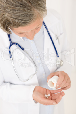 Senior doctor female hold pills looking down