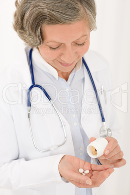 Senior doctor female hold pills looking down