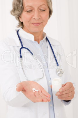 Senior doctor female hold pills looking down Senior doctor female hold pills looking down