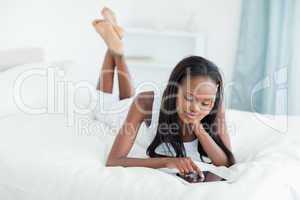 Woman using a tablet computer while lying on her bed
