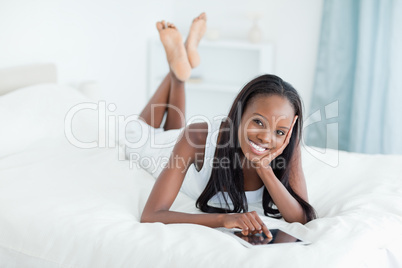 Woman lying on her bed with a tablet computer