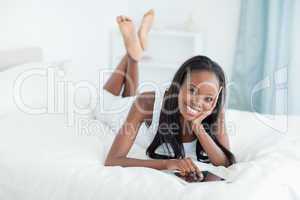 Woman lying on her bed with a tablet computer