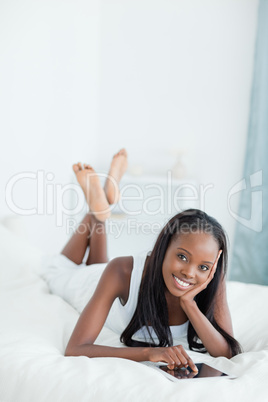 Portrait of a woman lying on her bed with a tablet computer