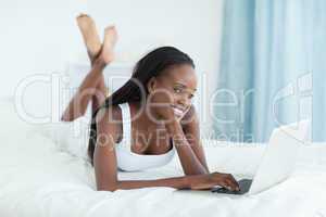 Smiling woman lying on her belly using a laptop