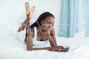 Young woman lying on her belly using a laptop