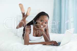 Happy woman lying on her belly using a laptop