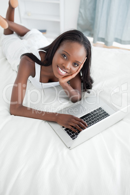 Portrait of a young woman lying on her belly using a notebook