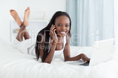 Happy woman using a notebook while making a phone call