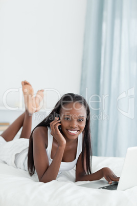 Portrait of a woman using a laptop while making a phone call