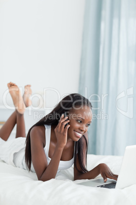 Portrait of a woman using a notebook while making a phone call