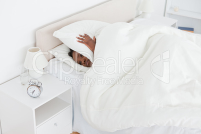Young woman being awakened by an alarm clock