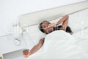 Cute woman yawning and stretching her arms while waking up