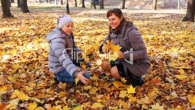 Mom And Daughter Scatter Leaves