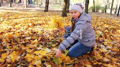 Girl Collects Leaves In Park