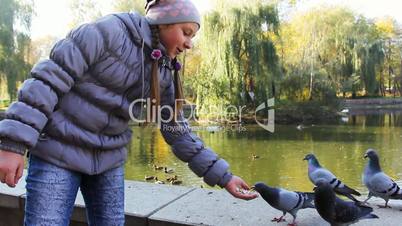 Girl Standing Feeds Pigeons From Hand