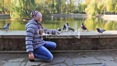 Girl Siting Feeds Pigeons From Hand