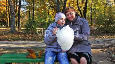 Mom With Daughter Sit And Eat Cotton Candy