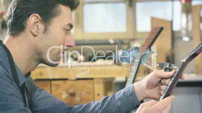 Young man working as craftsman in guitar workshop