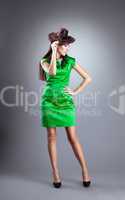 Young woman stand in green dress with hair hat