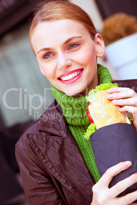 young smiling woman holding a sandwich