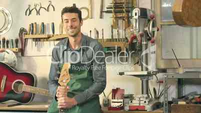 Happy Italian artisan at work and smiling in guitar workshop