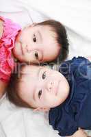 Twin baby sisters lay down in the bed