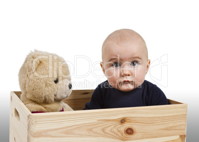 young child with toy in wooden box